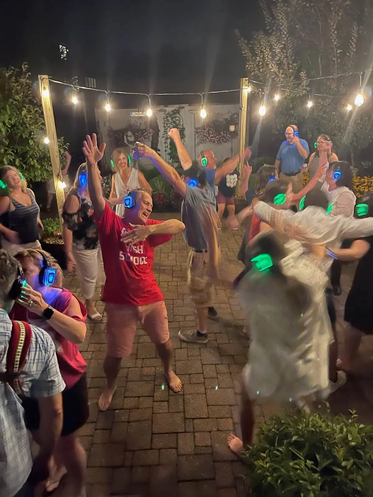 Backyard partiers dancing to with silent disco headphones